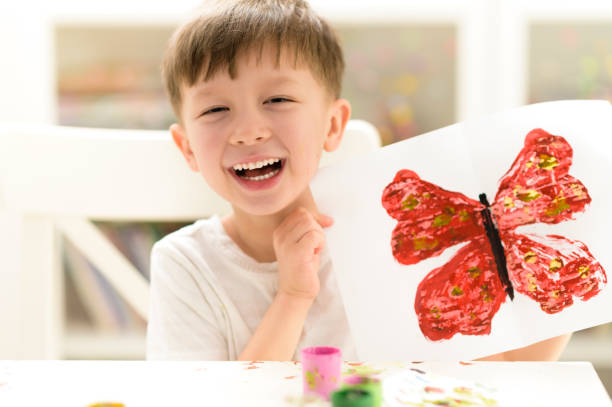 Proud kid showing his butterfly paint craft at kindergarten